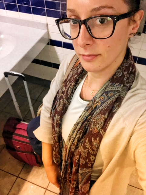 A bathroom selfie at Logan Airport with my carry on bag.